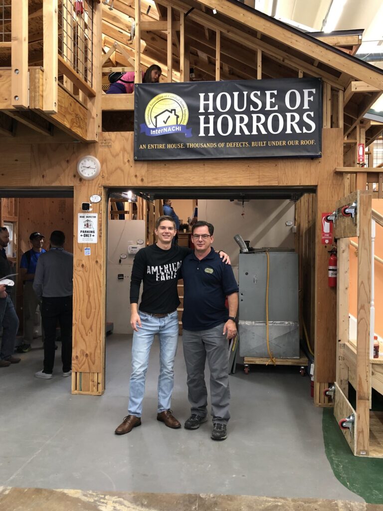 Aaron Shishilla, co-founder of WolfPack Advising, with his father John Shishilla of Honor Services beneath the InterNACHI House of Horrors banner