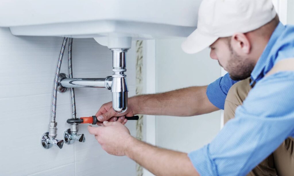 Plumber repairing pipes under a sink
