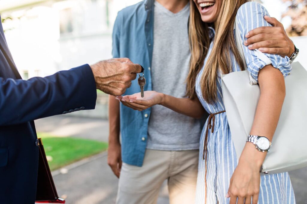 Happy couple receiving house keys from a real estate agent