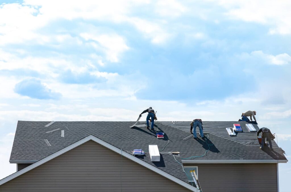 Roofers installing shingles on a residential roof