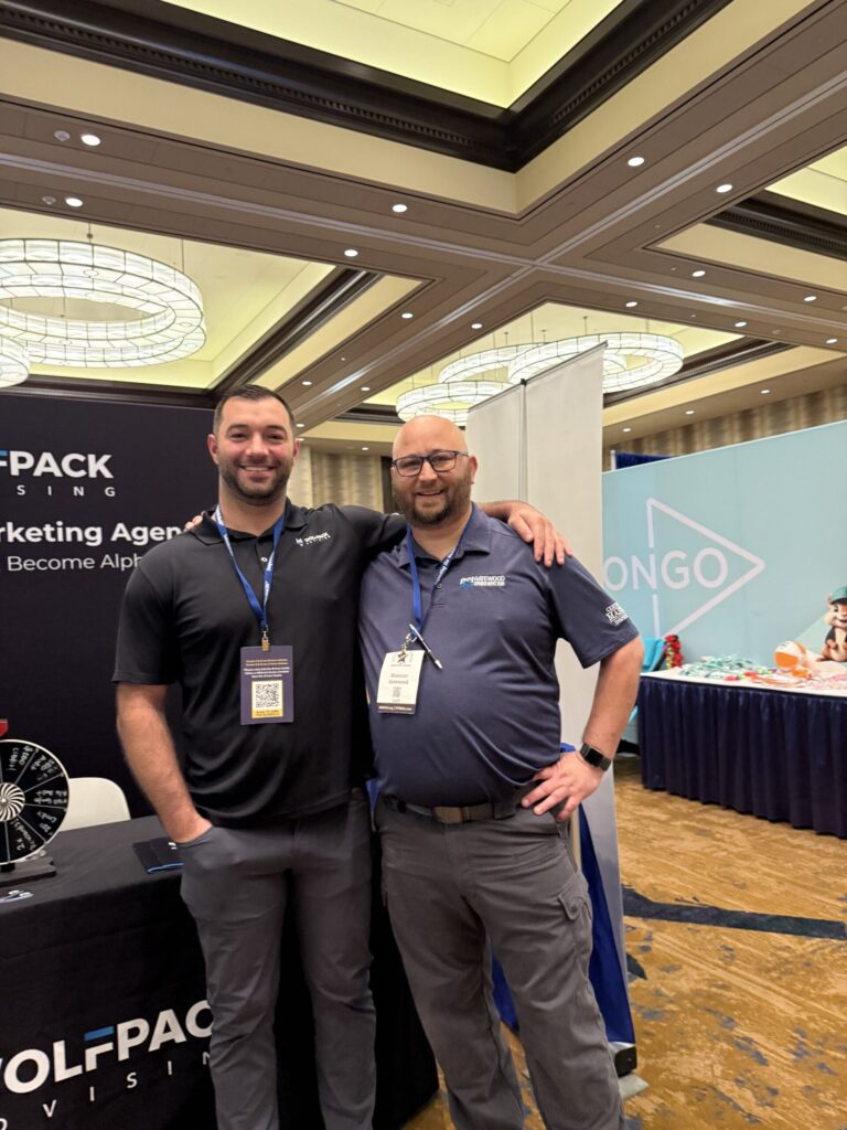 Two WolfPack Advising team members at the company booth at an industry conference